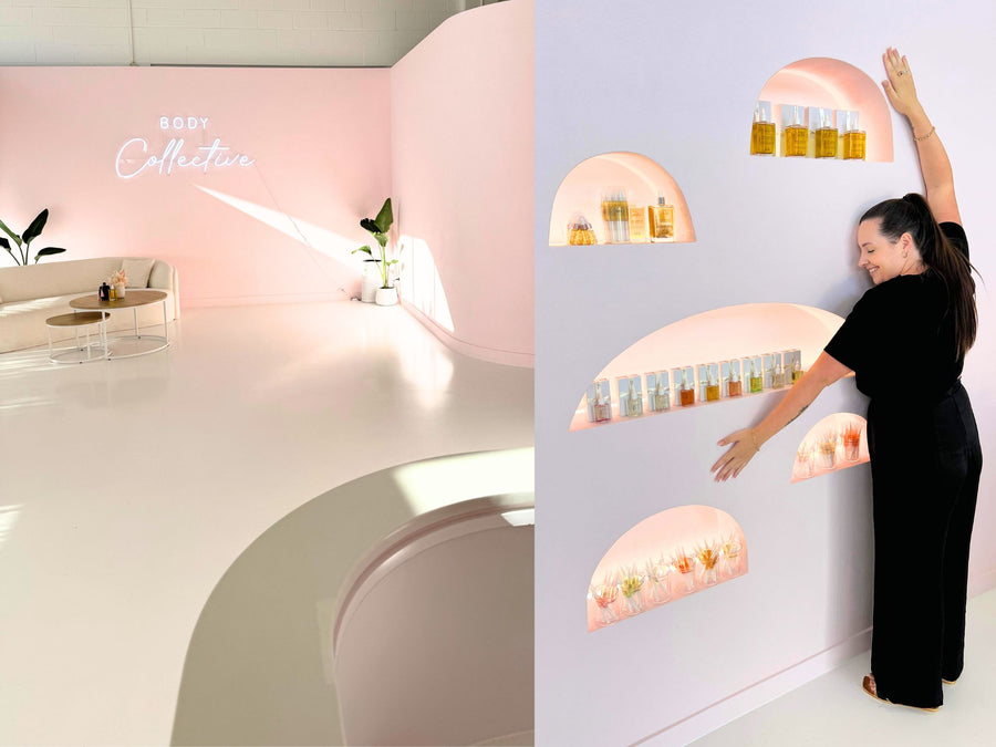 Salon interior with a neon sign, and a nail tech arranging nail serum bottles on an arched retail display wall